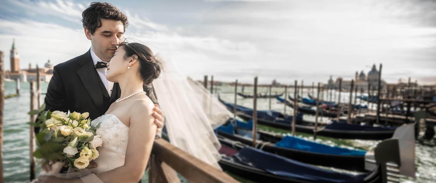 Sposi a Venezia con sfondo di gondole e isola di San Giorgio Maggiore