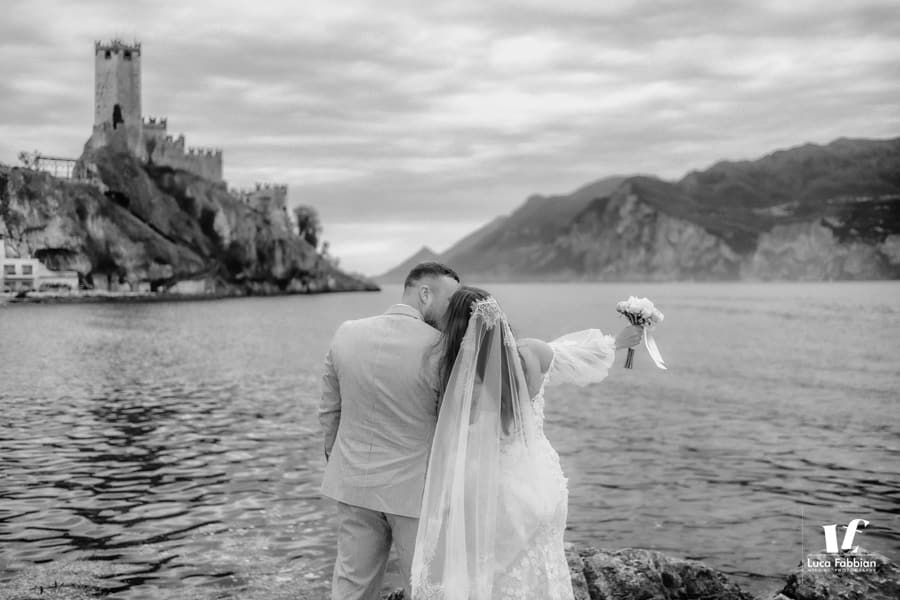 Foto degli sposi sul lungolago sotto il castello di Malcesine